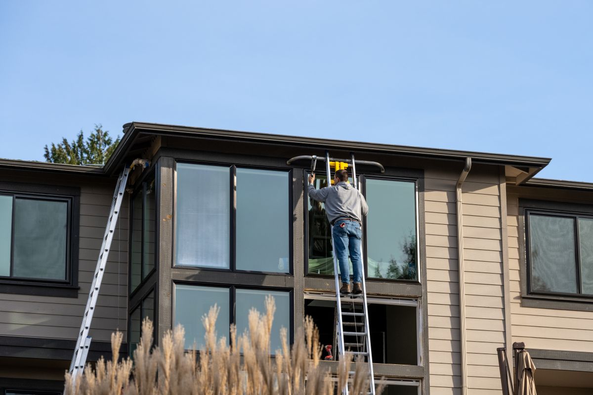 worker replacing window standing on metallic stairs siding wall